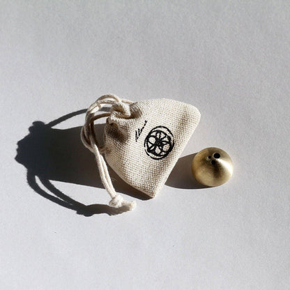 Small brass incense stick holder with a drawstring bag on a gray background