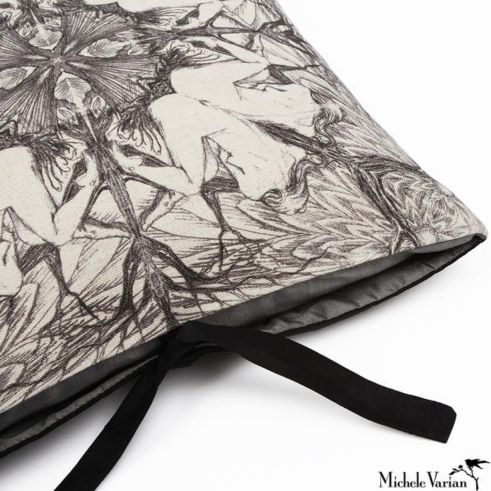 The top corner of a geometric black and white accent pillow with silk ties.