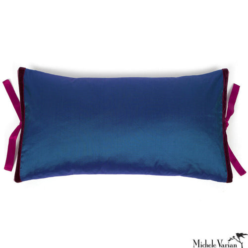 A deep blue rectangular silk pillow with fuchsia silk ties on a white background.